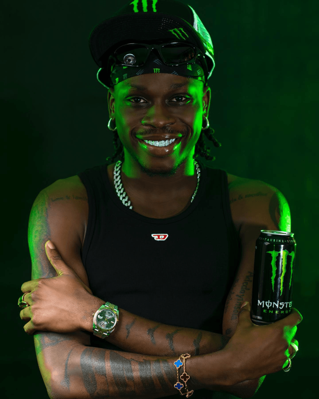 Fireboy DML wearing a monster drink with his hand folded